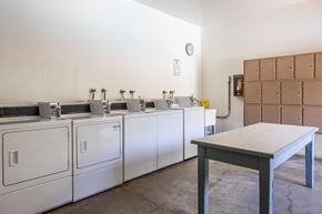 Los Angeles apartment for rent - a row of washers and dryers in a room with a table in the foreground