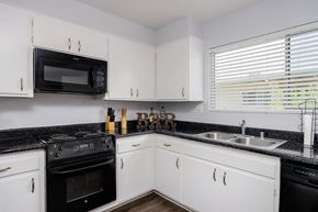 Chatsworth apartment for rent - a kitchen with white cabinets and black counter tops and black appliances