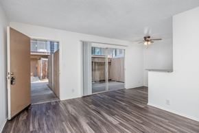 Gardena apartment for rent - an empty living room with a ceiling fan and sliding glass doors to a patio