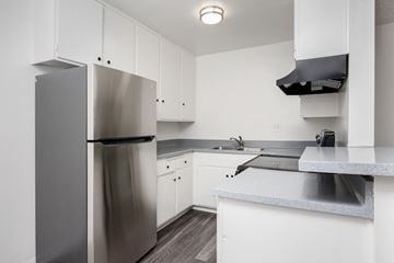 Gardena apartment for rent - a kitchen with white cabinets and a stainless steel refrigerator