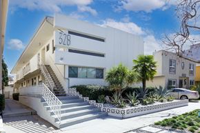 Beverly Hills apartment for rent - a white building with a staircase and palm trees in front of it