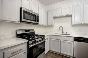Los Angeles apartment for rent - A kitchen with white cabinets and a black stove top oven.