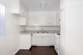Canoga Park apartment for rent - a kitchen with white cabinets and white appliances and a wood floor