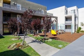 Northridge apartment for rent - a courtyard with a yellow swing set in front of a building