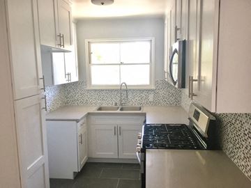 West Hollywood apartment for rent - a small kitchen with white cabinets and a stove and a window