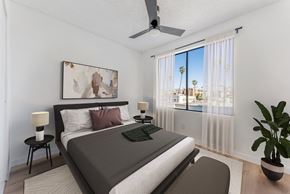 Los Angeles apartment for rent - A bedroom with a large bed, a ceiling fan, and a view of the outside through the window.