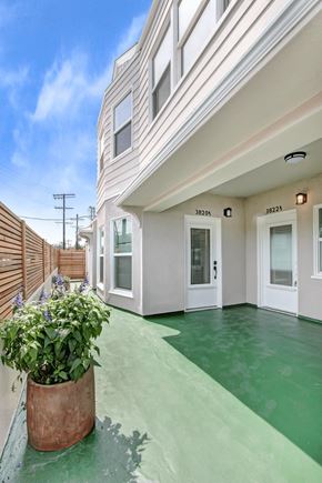 Los Angeles apartment for rent - the front entrance of a white house with a green sidewalk and a potted plant