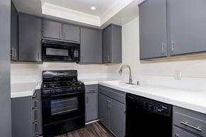 Redondo Beach apartment for rent - a kitchen with black appliances and white counter tops and gray cabinets