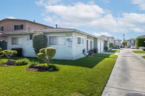 Gardena apartment for rent - a white house with a sidewalk and a lawn in front of it
