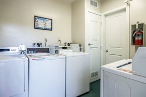 Long Beach apartment for rent - a laundry room with four washers and dryers and a door to a bathroom