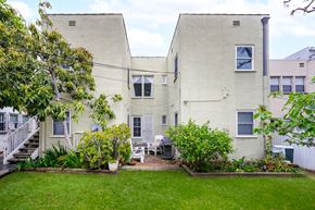 Beverly Hills apartment for rent - the backyard of a white apartment building with a lawn and plants