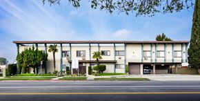 North Hollywood apartment for rent - a large building with palm trees in front of it on a street