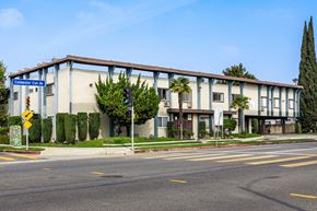 North Hollywood apartment for rent - a large building with palm trees in front of it on a street
