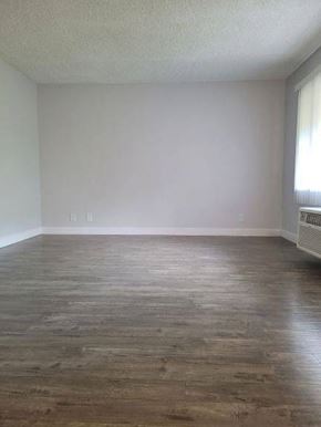 Whittier apartment for rent - an empty living room with wooden floors and a window