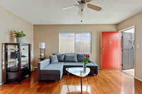 Los Angeles apartment for rent - A living room with a grey couch, a white coffee table, a ceiling fan, and a red door.