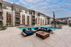 Austin townhouse for rent - A large outdoor pool area with a palm tree and seating area in front of apartment buildings.