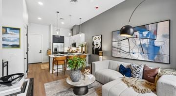 Las Vegas apartment for rent - A modern living room with a grey sofa, a coffee table, and a large abstract painting on the wall.