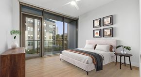 Las Vegas apartment for rent - A bedroom with a large bed and a view of a building outside the window.