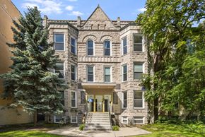 Chicago apartment for rent - A large, historic-looking building with a front porch and a tree in front.