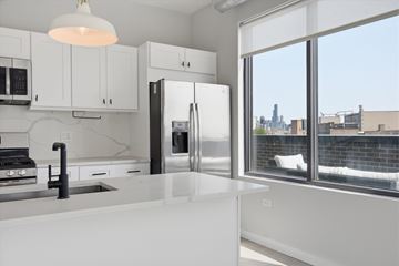 Chicago apartment for rent - A modern kitchen with white cabinets and a view of the city.