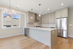 Chicago apartment for rent - a white kitchen with a large island and a stainless steel refrigerator