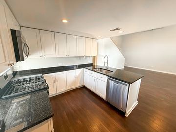 Oak Park apartment for rent - A kitchen with white cabinets and black countertops.
