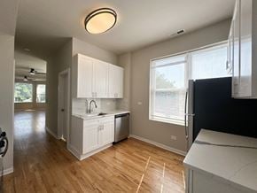 Chicago apartment for rent - A kitchen with white cabinets and a black fridge.
