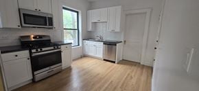 Chicago apartment for rent - A kitchen with white cabinets and black countertops.