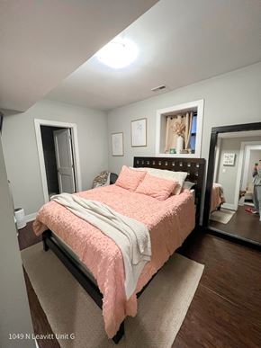 Chicago apartment for rent - a bedroom with gray walls and a pink bedspread