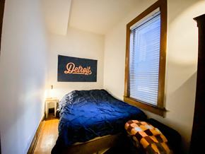 Chicago apartment for rent - A bedroom with a bed and a Detroit sign on the wall.