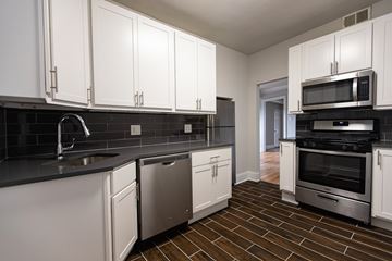 Chicago apartment for rent - A kitchen with white cabinets and black countertops.