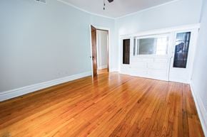 Chicago apartment for rent - an empty living room with wood floors and a door to a bedroom