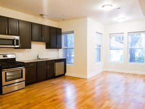 Chicago apartment for rent - an empty kitchen with black cabinets and a wood floor