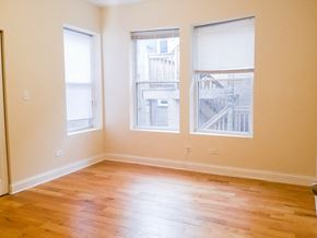 Chicago apartment for rent - an empty living room with wood floors and three windows