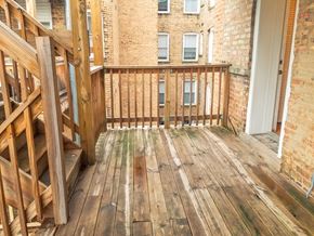 Chicago apartment for rent - a balcony with wooden floors and a brick building in the background