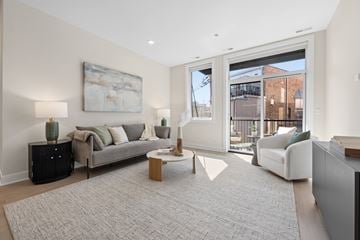 Chicago apartment for rent - A living room with a grey sofa, a grey rug, a wooden coffee table, and a painting on the wall.