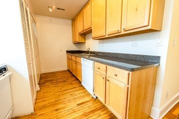 Chicago apartment for rent - A kitchen with wooden cabinets and a white dishwasher.