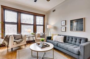 Chicago apartment for rent - A living room with a grey couch, a white coffee table, and a large window.
