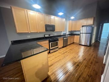 Chicago apartment for rent - A kitchen with wooden cabinets and black countertops.