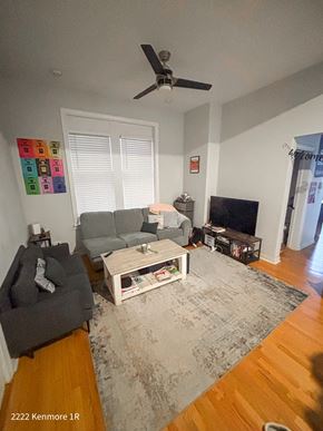 Chicago apartment for rent - A living room with a grey couch, a white coffee table, and a ceiling fan.