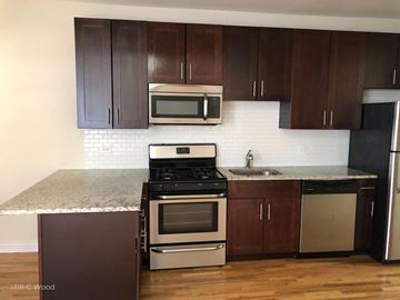 Chicago apartment for rent - a kitchen with dark wood cabinets and stainless steel appliances and a marble counter top