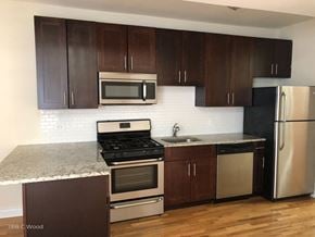 Chicago apartment for rent - a kitchen with wooden cabinets and stainless steel appliances and granite counter tops