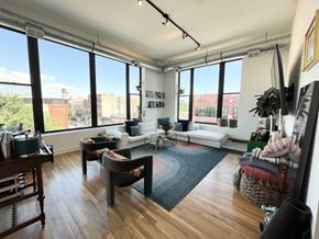 Chicago apartment for rent - A living room with a white couch, a grey chair, and a wooden table.