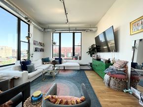 Chicago apartment for rent - A living room with a white couch, a coffee table, and a TV on the wall.