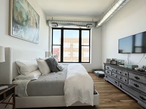 Chicago apartment for rent - A bedroom with a large bed, a dresser, and a painting on the wall.