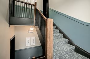 Chicago apartment for rent - A staircase with a wooden handrail and a light switch on the wall.