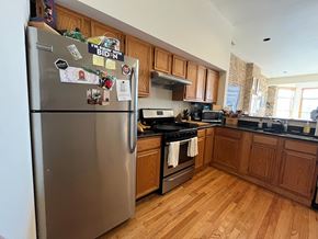 Chicago apartment for rent - A kitchen with a refrigerator covered in magnets and a stove top oven.