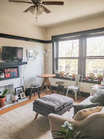 Chicago apartment for rent - A living room with a grey sofa, a white chair, a wooden table, and a television on a black stand.