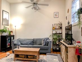 Chicago apartment for rent - A living room with a grey couch, a wooden coffee table, and a ceiling fan.