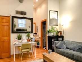 Chicago apartment for rent - A living room with a grey couch, a white desk, and a wooden floor.